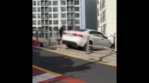 Driving through the car's fence on the sidewalk...hanging from the railing