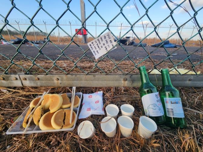 "Thank you, Captain".a glass and handwritten letter placed on a barbed wire fence at the scene of the disaster